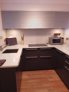 a kitchen with black cabinets and a microwave at APARTAMENTO MIRADOR DEL CADI in Puigcerdà