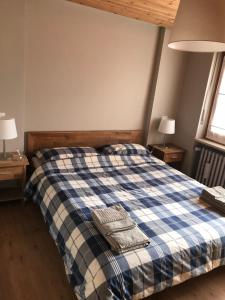 een slaapkamer met een bed met een blauwe en witte geruite deken bij Bardonecchia Holidays in Bardonecchia