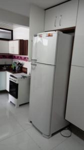 a kitchen with a white refrigerator and a stove at Apartamento em Guarapari in Guarapari