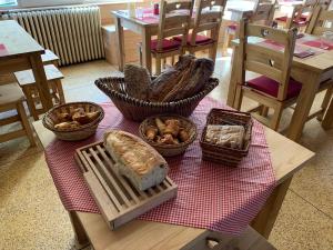 einen Tisch mit Brot und Körben sowie Tische mit Stühlen in der Unterkunft Hôtel l'Équipe in Le Sauze