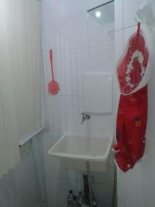baño con lavabo blanco y bolsa roja en la pared en Apart - em frente á praia dos milionários- Ilhéus, en Ilhéus