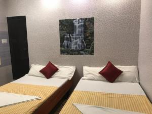 two beds with red pillows in a room at Rehoboth Home Stay in Kanyakumari