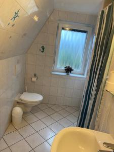 a small bathroom with a toilet and a window at Pension im Heidort in Oyten