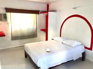 a bedroom with a white bed with a red frame at Hotel Maria Bonita Acapulco in Acapulco