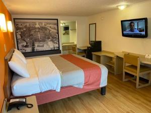Una habitación de hotel con una cama, un escritorio y un televisor. en FairBridge Inn Express London, en London