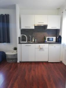 uma cozinha com armários brancos e piso em madeira em L4 - Green and cosy flat close Paris - WIFI & NETFLIX em Longjumeau