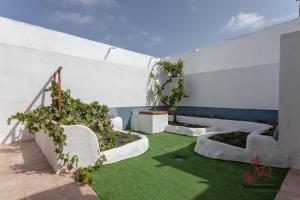 a garden with white walls and green grass at Casa Emblemática "Casa del Cuartel" in La Oliva