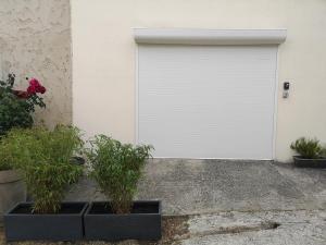 a white garage door with two potted plants at Saclay - Green and premium flat close Paris - WIFI & NETFLIX in Saclay