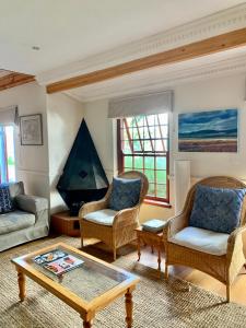 a living room with chairs and a coffee table at Chinta Cottage Hermanus in Hermanus