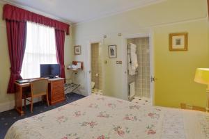 a bedroom with a bed and a desk and a television at 9 Green Lane Bed and Breakfast in Buxton