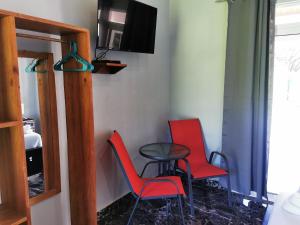 サマラにあるTuki Tuki Lodgeの椅子2脚、テーブル、テレビが備わる客室です。