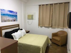 ein Schlafzimmer mit einem Bett und einem Stuhl und einem Fernseher in der Unterkunft Flat Angra Inn 220 Angra dos Reis in Angra dos Reis + 24 Fotos