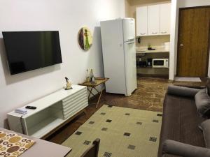 ein Wohnzimmer mit einem weißen Kühlschrank und einem TV an der Wand in der Unterkunft Flat Angra Inn 220 Angra dos Reis in Angra dos Reis