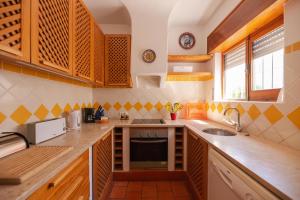 Oura Family House في ألبوفيرا: مطبخ مع خزائن خشبية ومغسلة