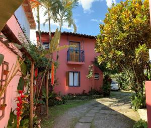 uma casa cor-de-rosa com uma palmeira à frente. em Pousada Manaca em Paraty