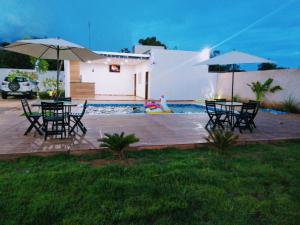 a patio with tables and umbrellas next to a pool at Flats e suítes Alegria in Olímpia