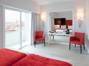 a bedroom with a bed and a desk and red chairs at Lutecia Smart Design Hotel in Lisbon