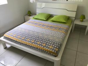 a bed with green pillows on it in a room at villa vue sur mer in Deshaies