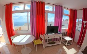 Habitación con cortinas rojas y escritorio con TV. en Apartamento ático, en Gran Tarajal