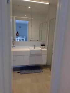 bagno con lavandino bianco e specchio di Luxury Beach Front Appartment a Rosebud