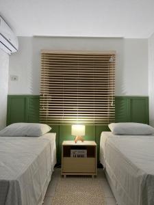 ein Schlafzimmer mit 2 Betten und einem Tisch mit einer Lampe in der Unterkunft Adorável Casa em Cond de frente para a Praia Rasa in Búzios