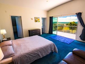 a bedroom with a large bed and a large window at La Casa Al Mare - Golden Bay Beach House in Tasman