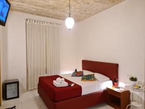 - une chambre avec un lit rouge et une télévision dans l'établissement I Dormienti, à Rome