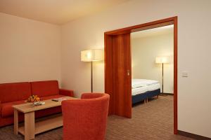 a room with a couch and a table and a mirror at H+ Hotel Wiesbaden Niedernhausen in Niedernhausen