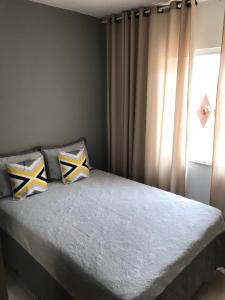 a bedroom with a bed with two pillows and a window at Apartamento Cantinho da Serra in Nova Friburgo