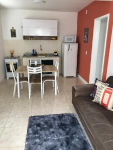 Apartamento Cantinho da Serra في نوفا فريبورغو: غرفة معيشة مع أريكة وطاولة ومطبخ