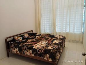 a bedroom with a bed with a floral bedspread at HOMESTAY EIJAZ KUALA ROMPIN in Kuala Rompin