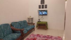 ein Wohnzimmer mit 2 Stühlen und einem TV in der Unterkunft HOMESTAY EIJAZ KUALA ROMPIN in Kuala Rompin