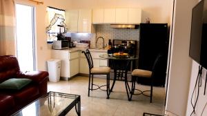 a kitchen with a small table in a kitchen with a couch at Blue Star Apartments & Hotel in Lance aux Épines