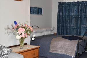 a bedroom with a bed and a vase of flowers on a table at Olivista in Masterton