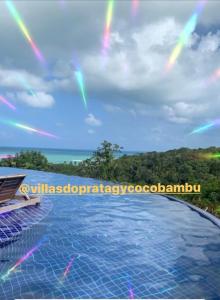 una piscina con un arco iris en el cielo en Villas do Pratagy CocoBambu en Maceió