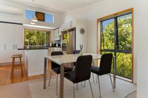 a kitchen and dining room with a table and chairs at The Cove at Little O in Oneroa