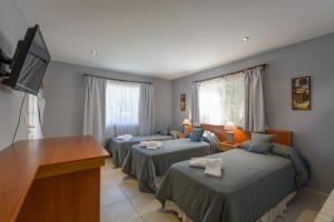 Habitación con 2 camas, escritorio y TV. en Las Acacias en Villa La Angostura