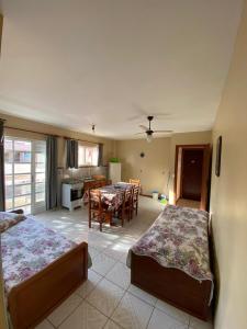 a bedroom with two beds and a dining room with a table at Departamentos Vale Encantado in Bombinhas