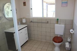 a bathroom with a toilet and a sink and a window at Yvonnes Rest Holiday Home in Bridgetown