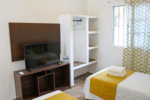 a room with a television and a bed with a yellow blanket at Rooms in Cancun Airport in Cancún
