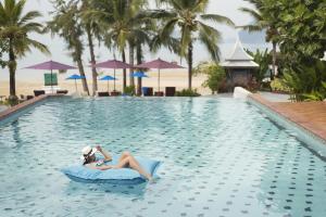 a woman laying on a raft in the swimming pool at a resort at Anyavee Tubkaek Beach Resort- SHA Plus in Tab Kaek Beach