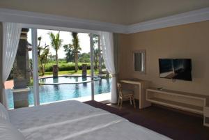 a bedroom with a bed and a view of a pool at Kori Maharani Villas - Lagoon Pool Access 6 in Siyut