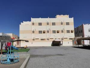 um grande edifício branco com um parque infantil em frente em Salassel Al Jabal Al Akhdar Guesthouse em Al ‘Aqar