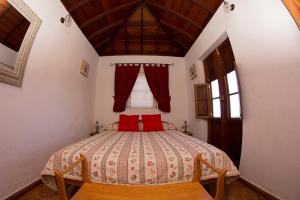 a bedroom with a bed with red pillows and a window at Casa Micaela in Garafía