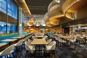 a restaurant with tables and chairs and a mural at The Manohara Hotel Yogyakarta in Yogyakarta