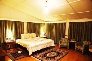 a hotel room with a bed and two chairs at Springfields - A Heritage Palace Since 1902 in Shimla