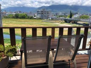 Duas cadeiras sentadas numa varanda com vista para a cidade em Two Dots On Line Homestay em Hualien City