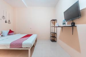 um quarto com uma cama e uma televisão de ecrã plano em Super OYO 2034 Eden Guest House em Depok