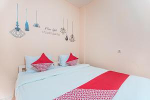 um quarto com uma cama com almofadas vermelhas e brancas em Super OYO 2034 Eden Guest House em Depok