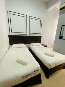 two beds in a room with white sheets and pillows at Gorjes Inn KLIA & KLIA2 in Sepang